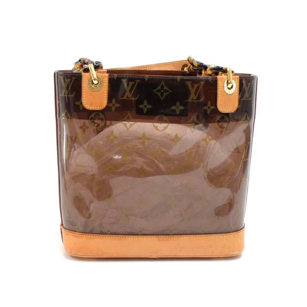 Louis Vuitton Sac Ambre PM in monogram vinyl and brown leather pieces from the Louis Vuitton Cruise Collection. It features a structure of clear Vinyl enforced with leather trimming and bottom. Has tortoiseshell style chain links for handles. It