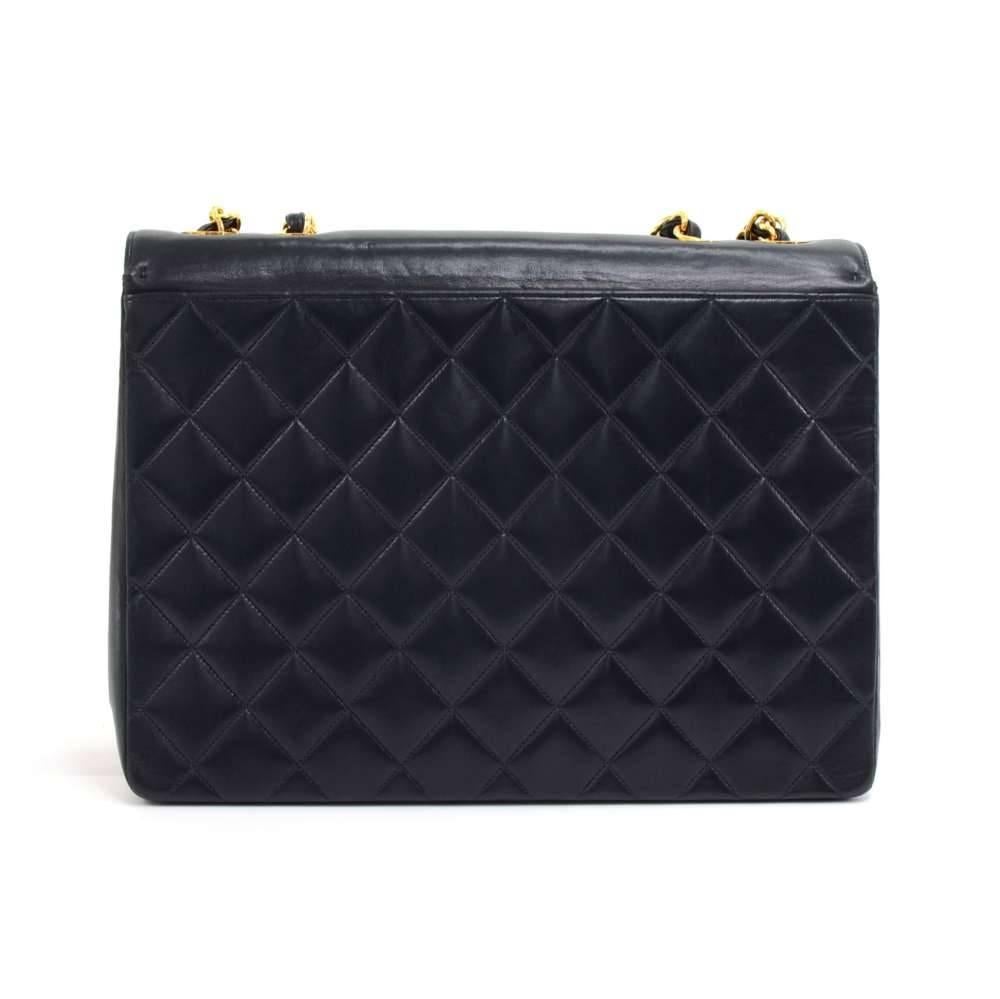 Vintage Chanel Shoulder Flap bag in navy lambskin leather. It has flap top with a large CC logo stitched and embossed with a gold-tone CC twist lock beneath it. The back and underneath the top flap has the classic quilted leather. There is also one