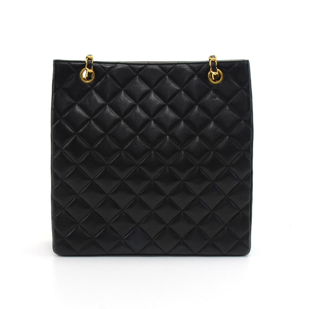 Vintage Chanel Tall Shoulder bag in Black quilted lambskin leather. It has the classic double C Chanel logo on the top center. Main access is secured with two stud buttons. Inside is lined with the classic Chanel red leather and has 1 zipper and