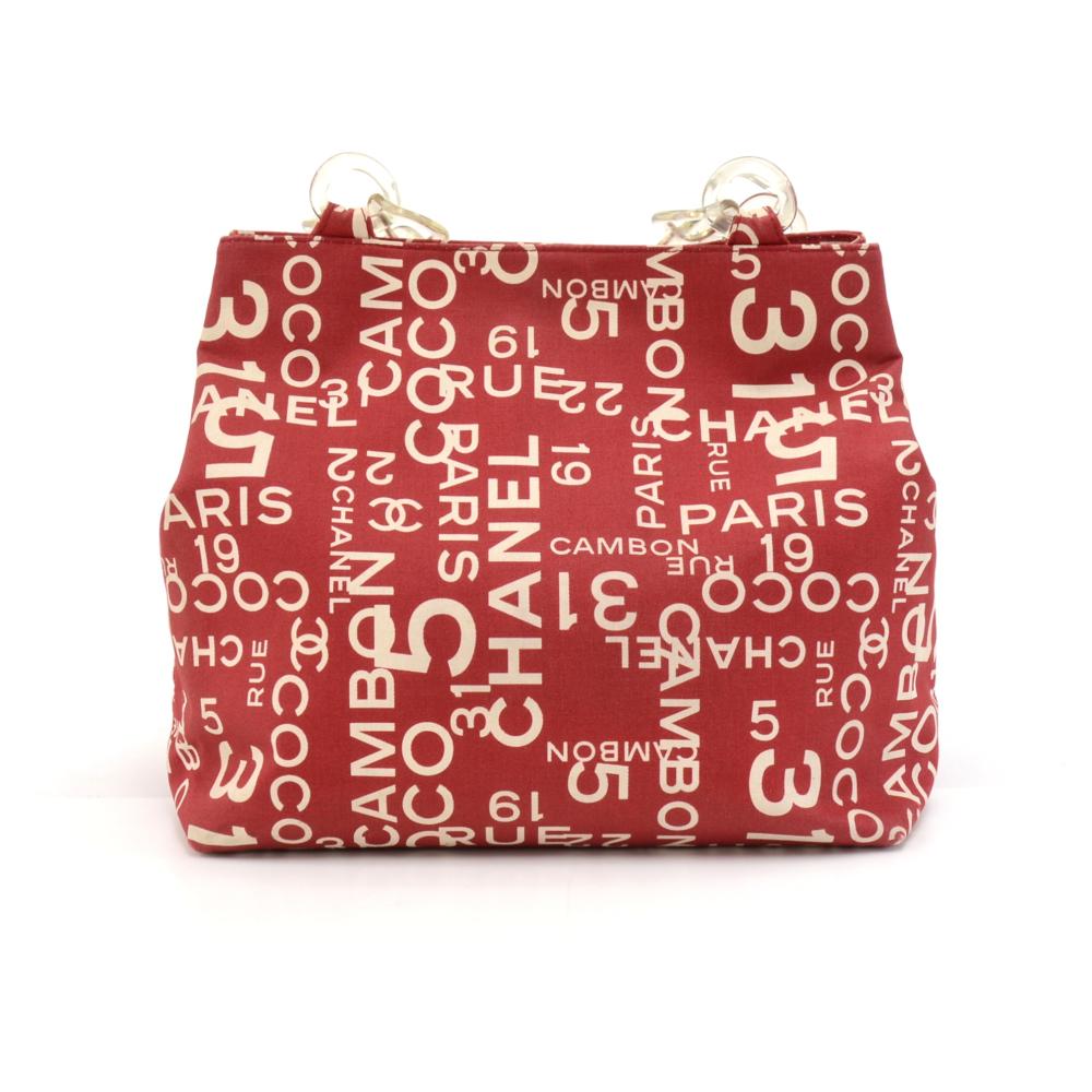 Chanel Tote Bag in Red Logo mania canvas. Has lucite chains for the double shoulder straps. Main access is secured with a magnetic closure. Inside is lined with Off white fabric and has one zipper pocket and one detachable (snap buttons) flat pouch