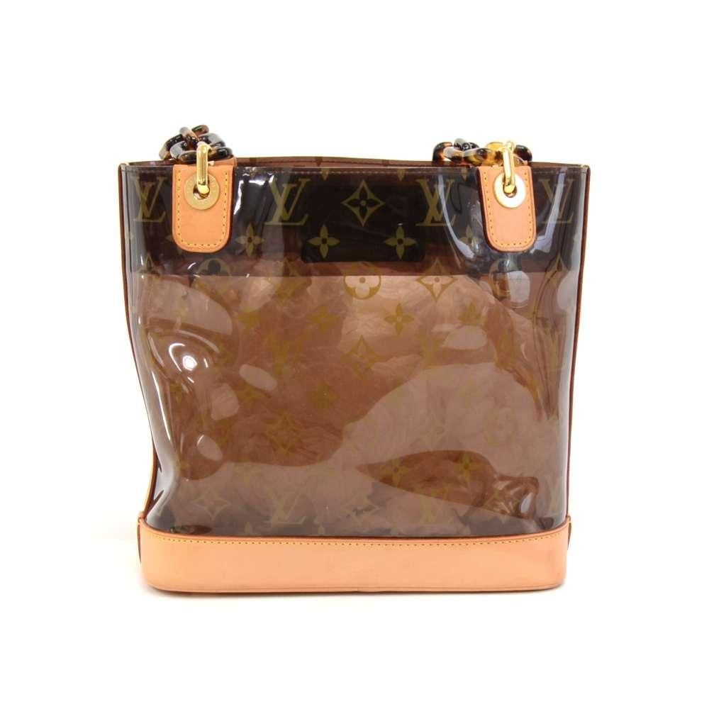 Louis Vuitton Sac Ambre PM in monogram vinyl and brown leather pieces from the Louis Vuittons Cruise Collection. It features a structure of clear Vinyl enforced with leather trimming and bottom. Can be carried in hand or shoulder with tortoise shell