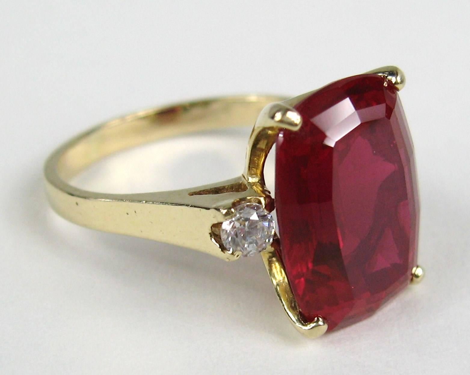 Stunning large center synthetic Ruby gem with two diamonds flanking each side of the stone. 
Set in 14K Gold 
Ring is a size 10 and can be sized by us or your jeweler 

Any questions please call or hit request more information 