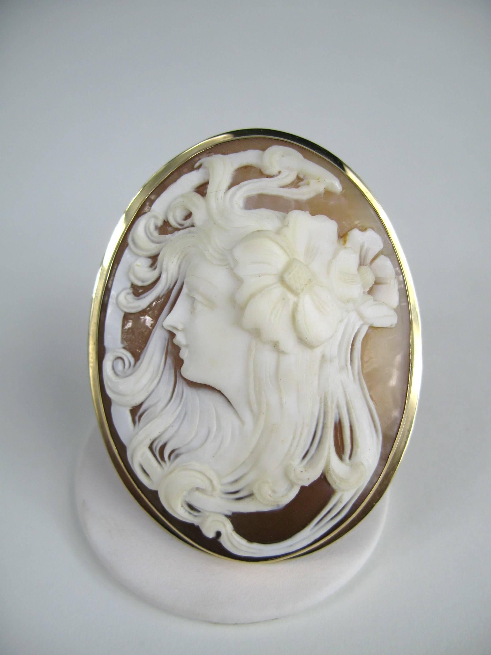 Take a look at this cameo set in 14K gold 
Side profile of a Victorian woman with her hair tussled and a large flower in her hair 
Measuring 2.50