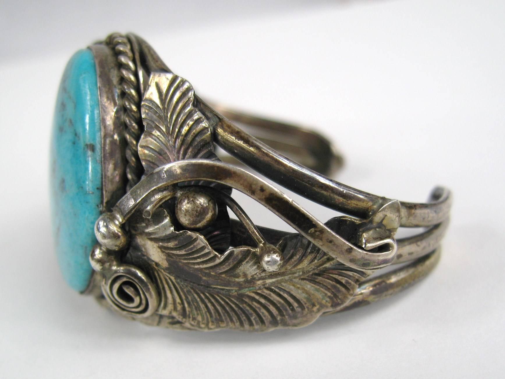 Gorgeous American turquoise set in sterling silver by Navajo silversmith, signed sterling with illegible Hallmark 
Large turquoise stone in the center, feather detailing with a 3 row cuff. 
1.50 top to bottom on the stone, opening is 1.08 
I have a