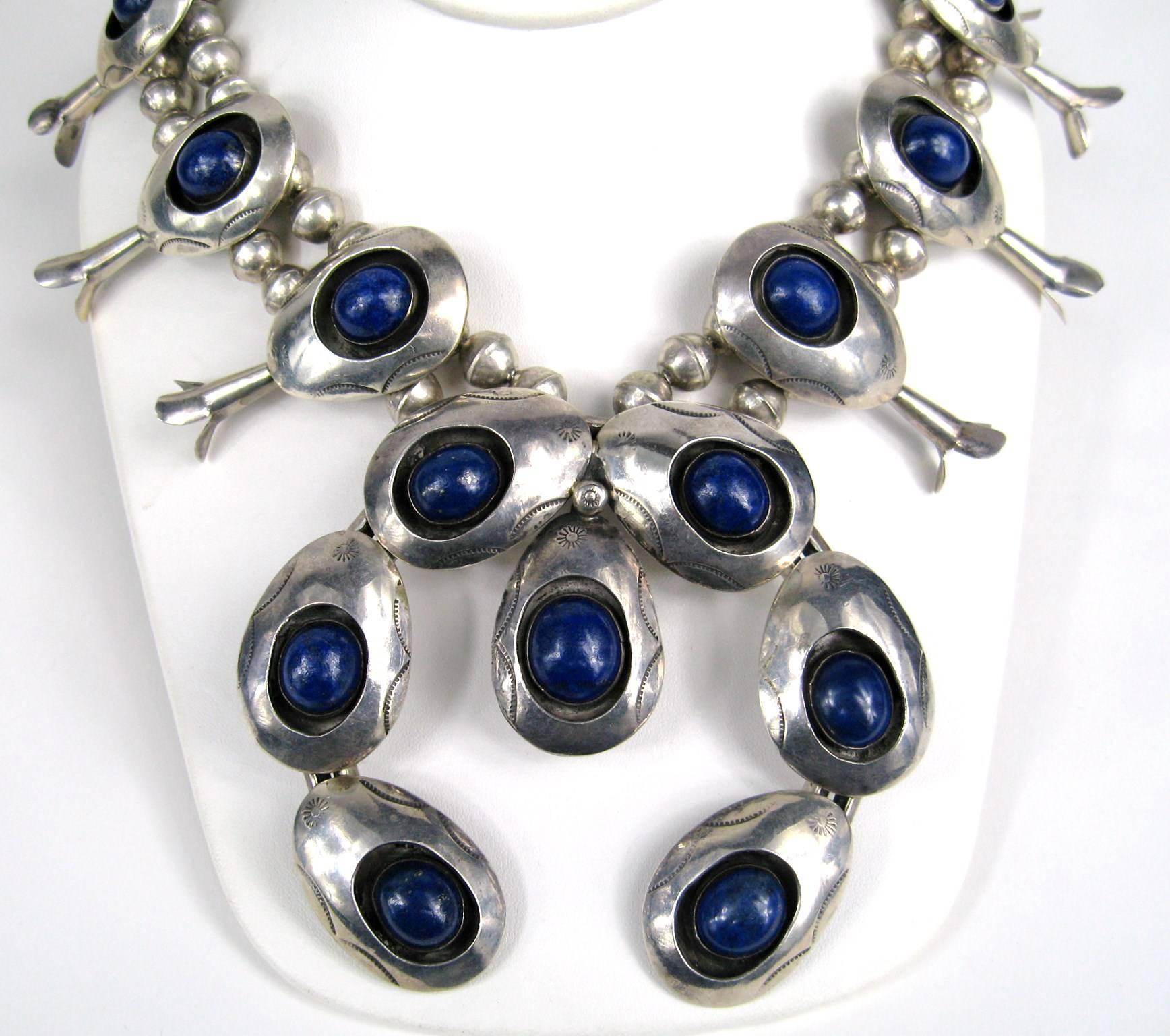 This is an amazing piece of Navajo Jewelry! Lapis lazuli Shadow Box Squash Blossom. 10 Lapis stones inset in sterling blossoms attached to a double bead sterling chain. It graduates to a single strand closer to the hook and eye closure. The blossoms