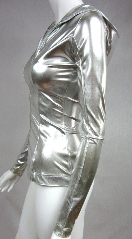 The 80s are calling! This  silver metallic vinyl hoodie from Ms Norma Kamali is fabulous. Please excuse the colors you see they are only a reflection. Zips up the front. Sleek skin tight fit. Has a lot of stretch to it, however this is a XS.  Up to