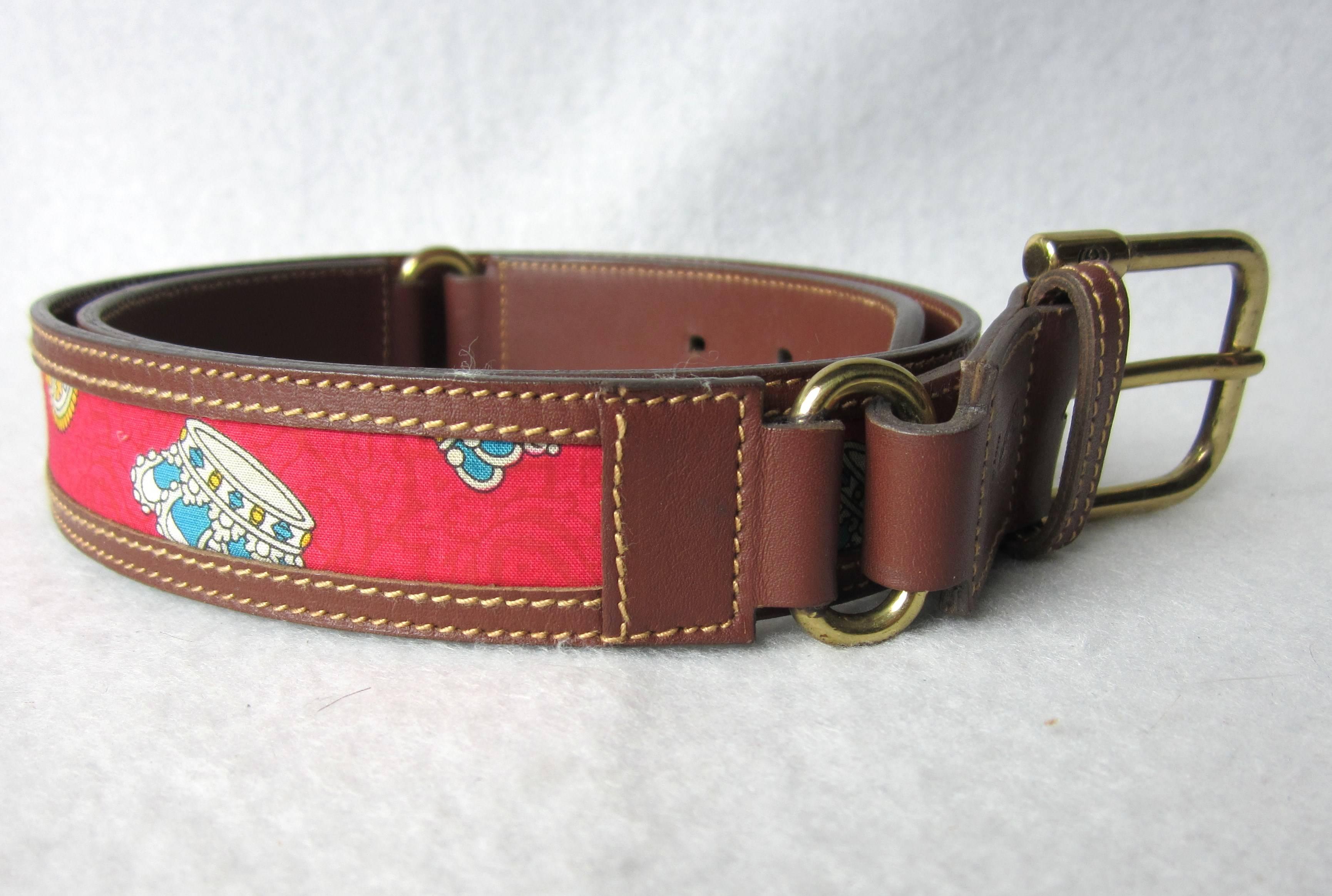 Rich brown leather with Red background material depicting a king's Crown. Labeled 85-34. Has Gold tone Hardware Measuring 1.15 inches wide. It's 35 inches long 1st belt hole at 31.5 inches. This is out of a massive collection of Contemporary Fashion