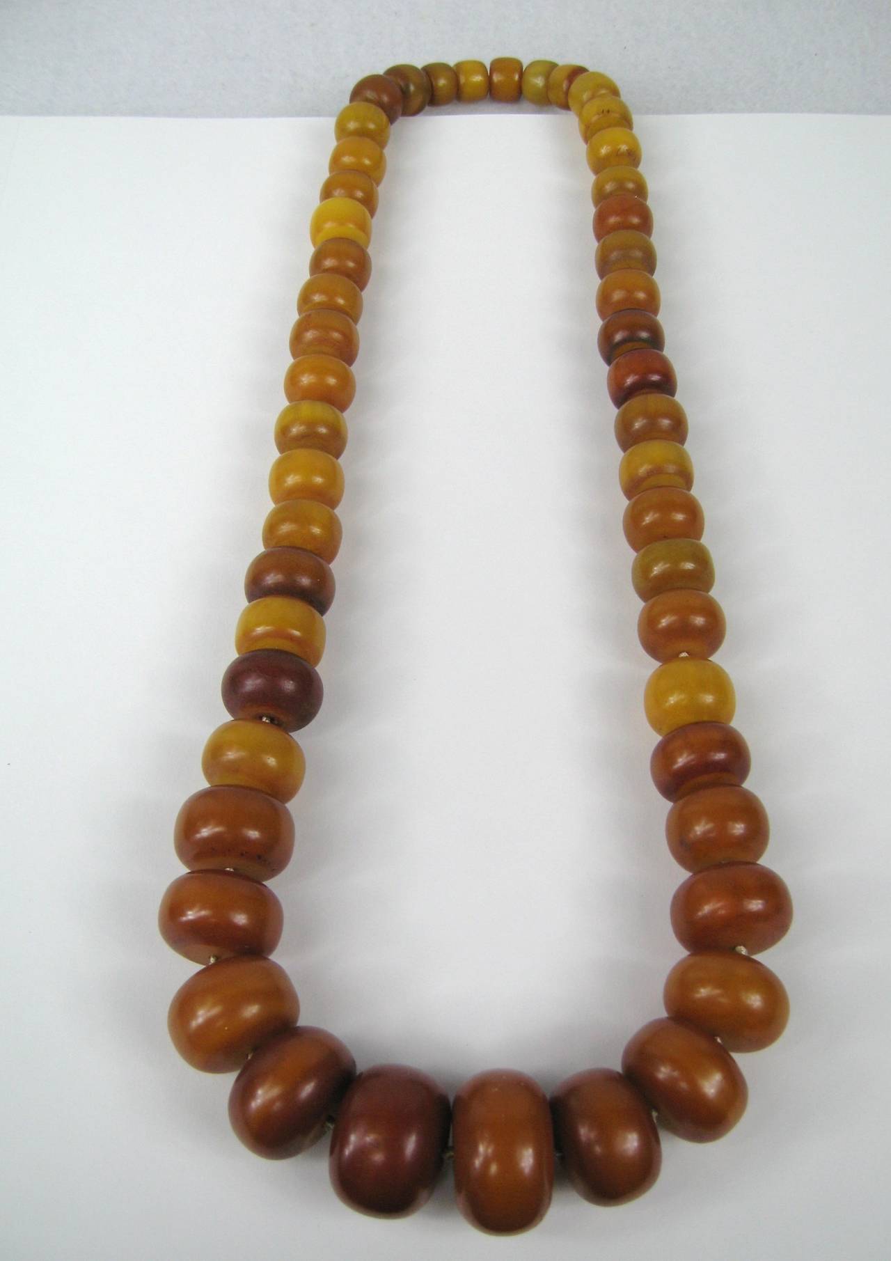 Wonderful early Amber Bakelite necklace. Beads graduate in size from 1.29 in or 32.63mm x.76 in or 19.50mm down to .43 inches or 11.7mm x .58 inches or 14.77mm. 30 inches long. No clasp, goes over you head. This is out of a massive collection of