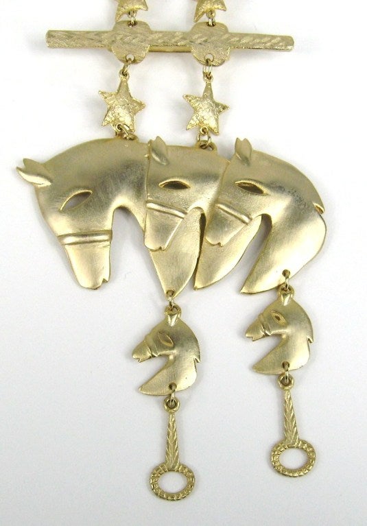 Very Interesting Brooch Gold Tone Horses with horse charms dangling from the bottom. This gets Pinned to your shoulder and the Horse heads hang down on both sides of your garment. Measures 3.8 inches  wide x 5.5 inches long on each side. This is out