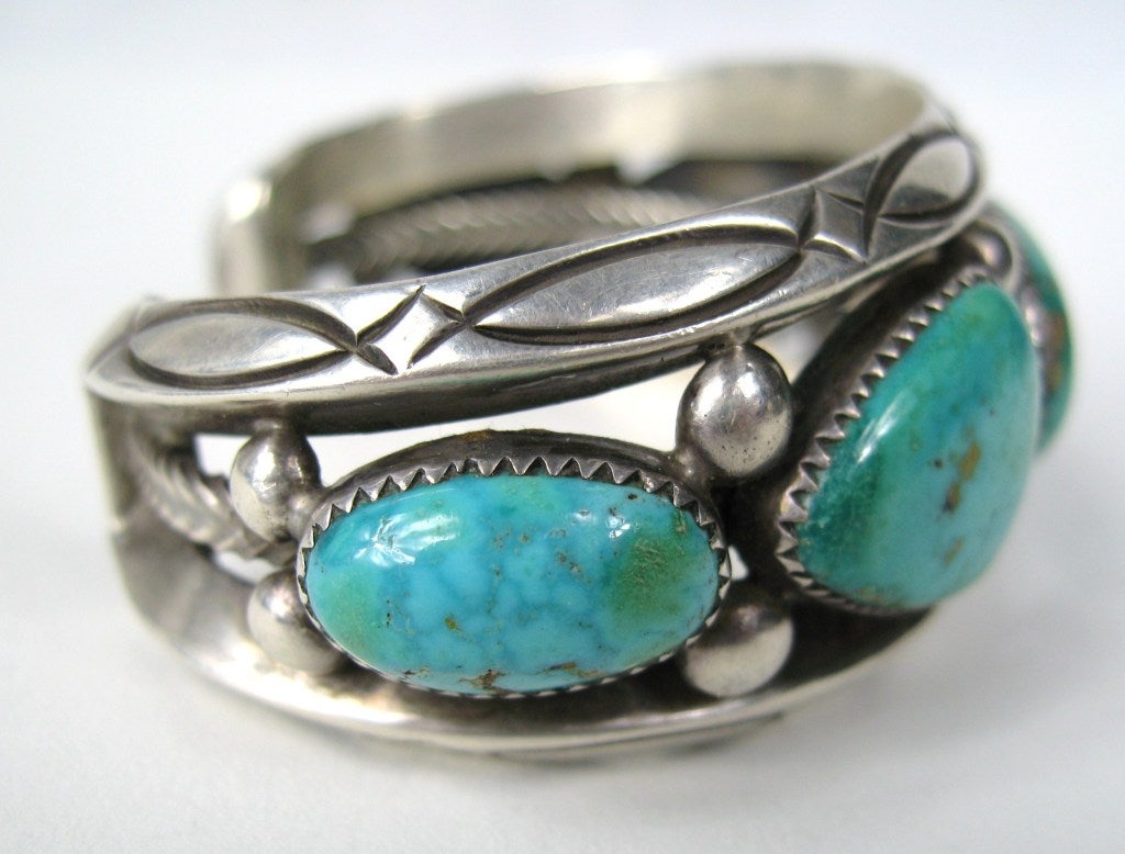 Navajo Silver Smith Tsinnie creates amazing works of art. This bracelet is handcrafted in sterling set with 5 stunning Turquoise stones. It measures 1.14 inch wide. 5.25 inside bracelet with Opening of 1.20 in. Has a bit of give to make it larger or