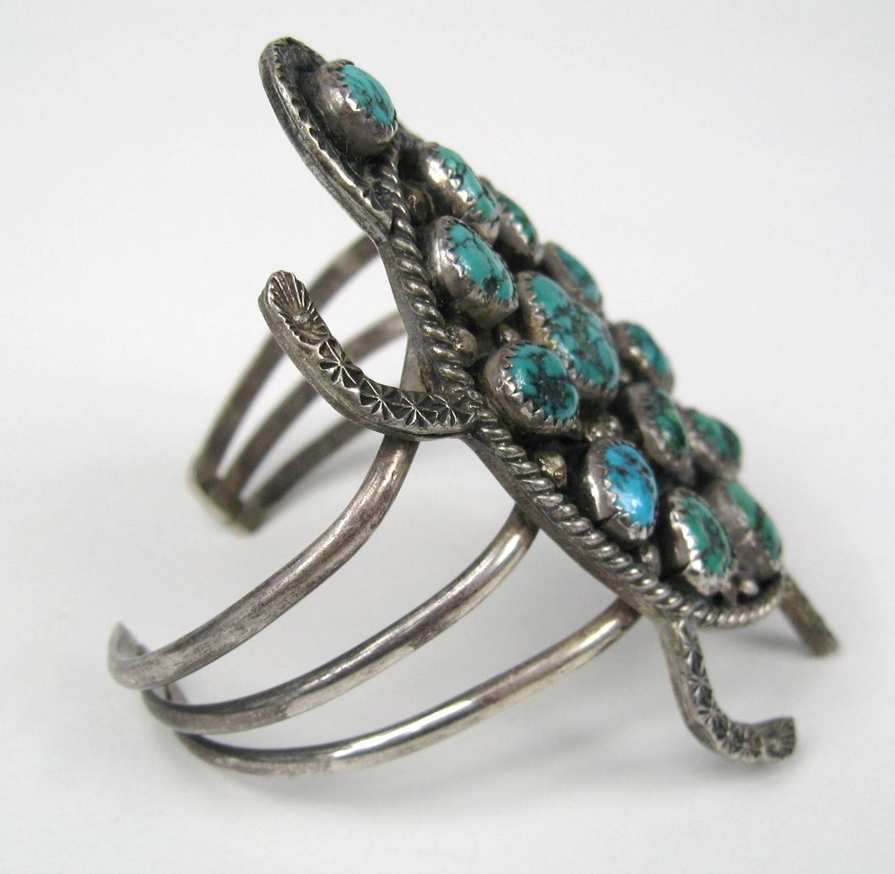 Older Turtle formed from the artistry of the Native Americans. This is a spectacular 3 band bracelet with amazing detailing that makes up the Turtles body. 13 Turquoise stones Measures 3.27 in top to bottom on the Turtle Opening measures 1.07 in.