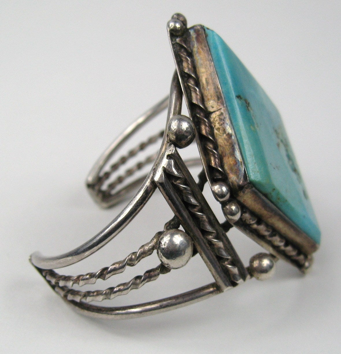 Bracelet en argent sterling fait à la main avec une superbe pierre turquoise en forme de diamant. La pierre mesure 2,20 pouces de haut en bas x 1,50 pouce de large. Il est possible de l'agrandir ou de le rétrécir. L'ouverture dans le dos mesure 1,40