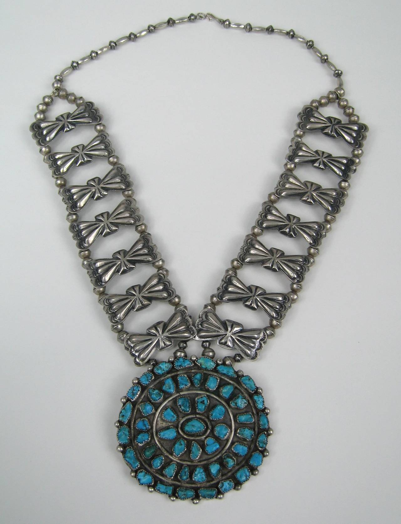 Massive handmade Turquoise hanging from a butterfly motif necklace. The craftsmanship on this is stunning. The oval has a pin back on it. The oval drop measures 3.22 in wide  x 3.09 in high. The links are 1.77 in x .78 in set on a double beaded