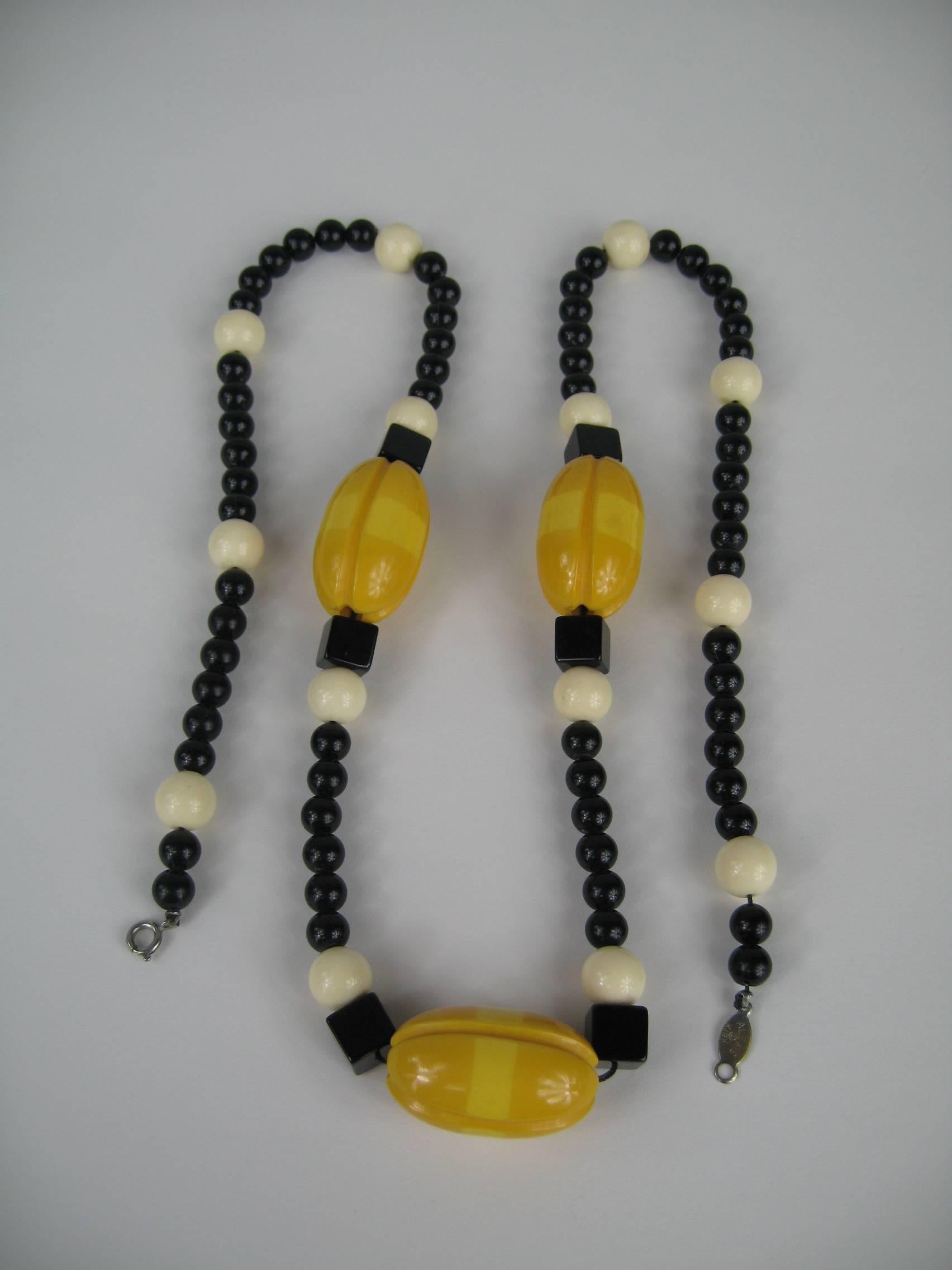 Ce collier vintage en bakélite présente des couleurs étonnantes. Bakélite de couleur ambre avec des perles noires et crème mélangées. Perles en bakélite sculptées surdimensionnées avec des perles en matériaux mixtes - mesurant 34 pouces d'un bout à