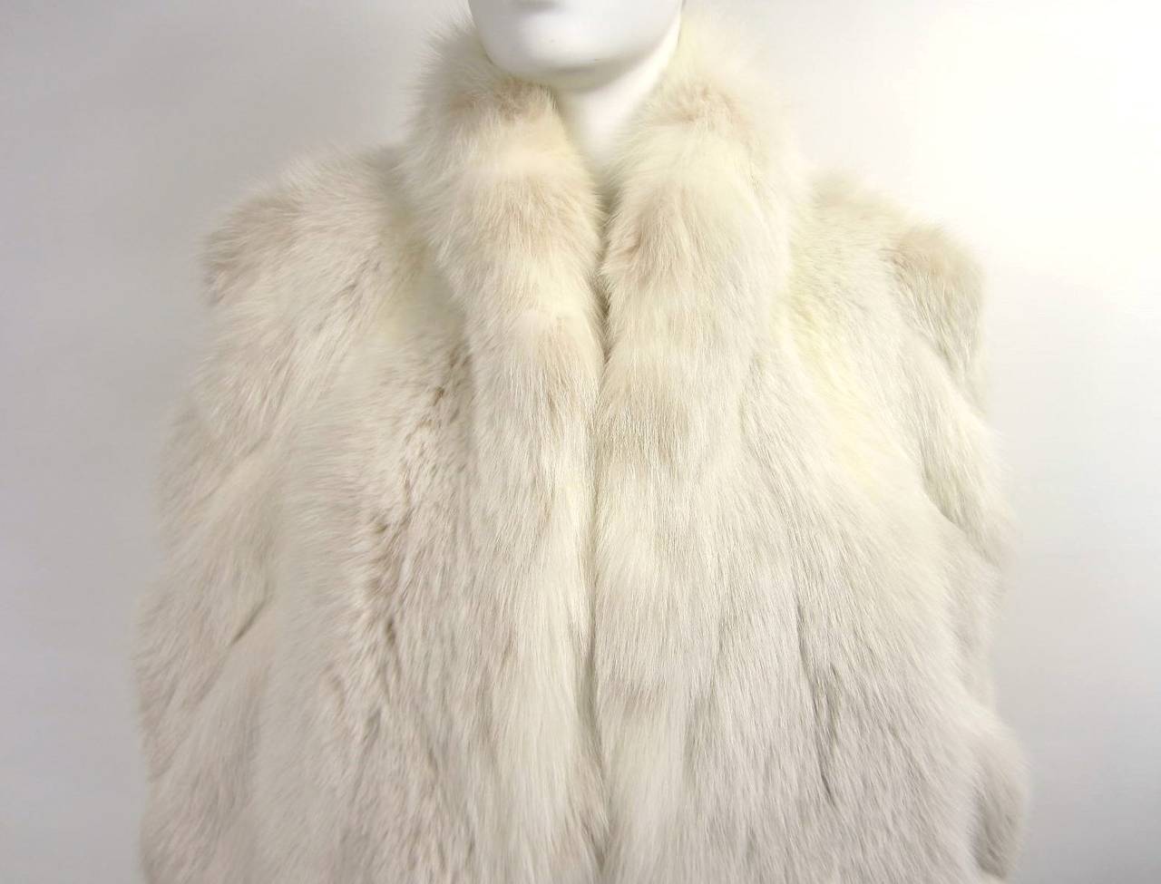 This is a Gorgeous white Fur Fox Coat. Gorgeous Swirl Detail on Sleeves, Oversized sleeves. There is a peach hue to the collar, French Hem, Lining has a bit of yellowing at the collar Side slit pockets. Measures Bust 40 Waist 42 Hips 48 Length 30