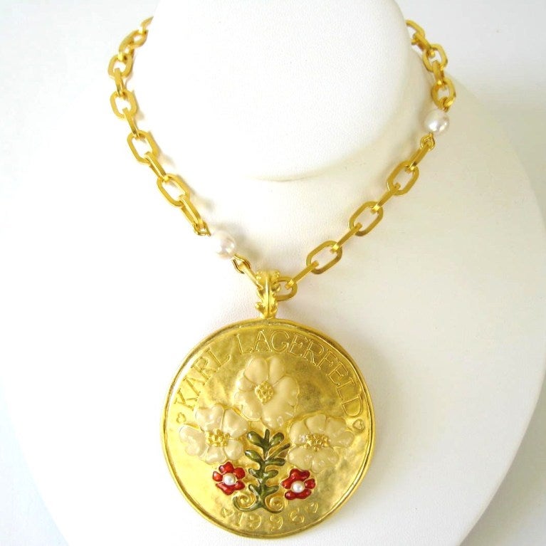 Stunning Lagerfeld Piece. Floral Motif, Enamel on the flowers are done in Red, green and Tan. Karl's name engraved at the top and dated at the bottom. Long Large Link chain with Pearl accents. It can be double around your neck for layering. 34