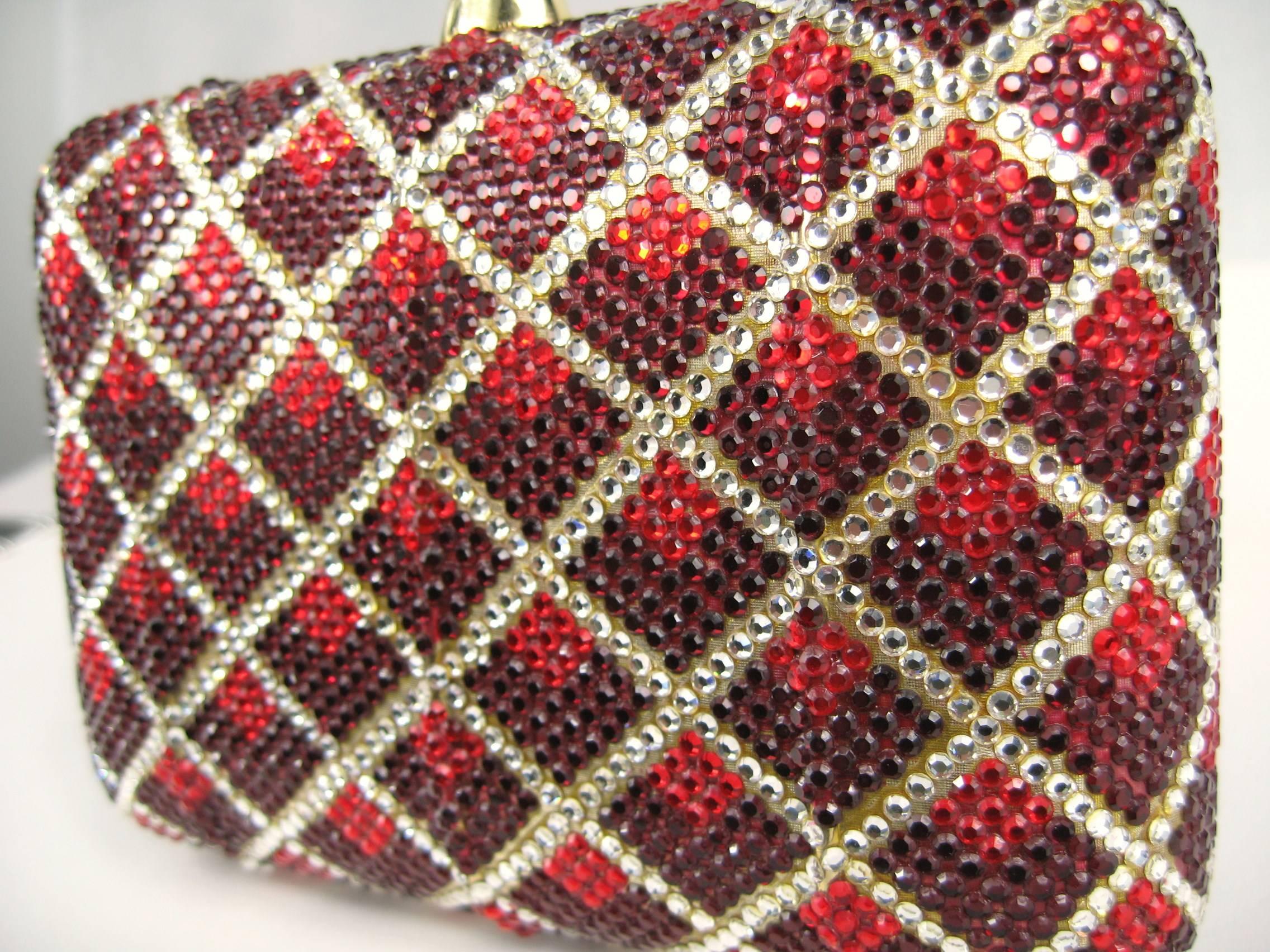 Stunning Clear and Red Swarovski Crystal on this magnificent Judith Leiber Clutch. A must-have for the upcoming holiday season, as well as any black tie event. Runway ready! Gold leather interior that holds an attached chain shoulder strap