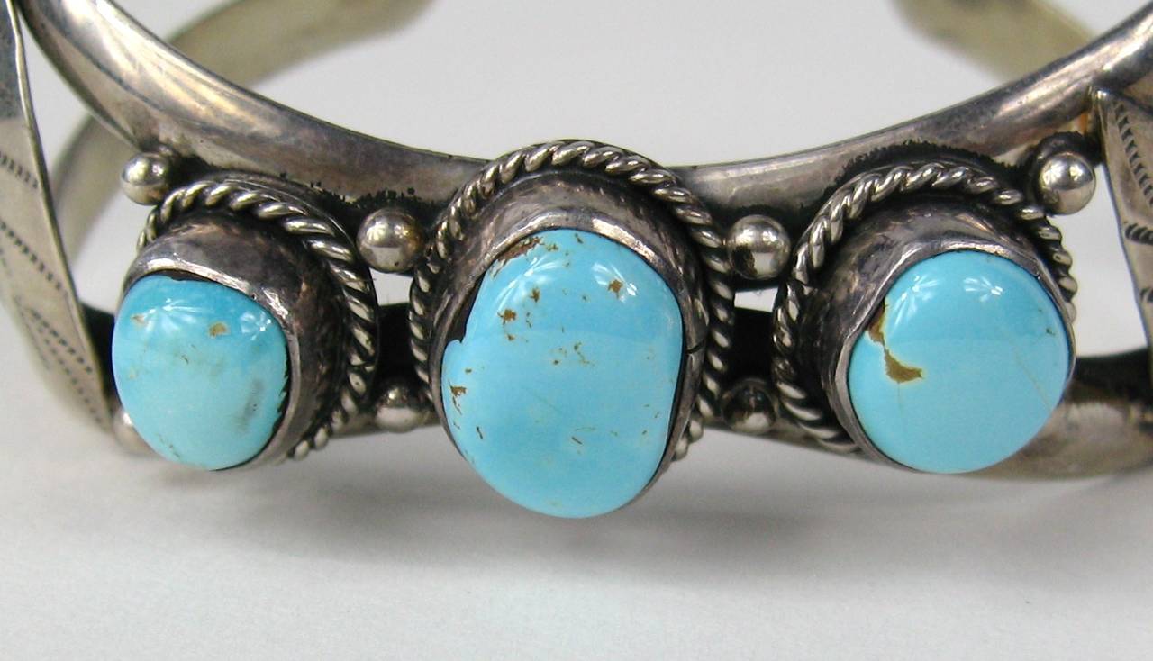 Three large turquoise stones set in bezel sterling with braided motif surround with a Leaf motif at each end. Double wire cuff. Hallmarked B W Z 
Measuring  .98 in at the widest down to .62 in at the center turquoise stone.  Will fit a 6-7 inch