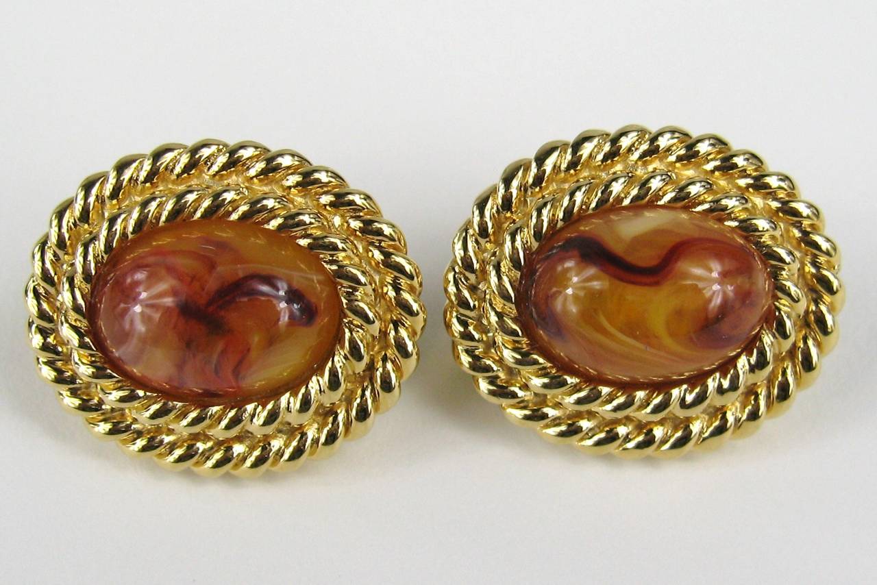 Purchased in the late 1980s from Neiman Marcus stored away till now. Tags still attached. Clip On's. Rope gold gilt surrounding a faux amber stone 
measuring 1.15