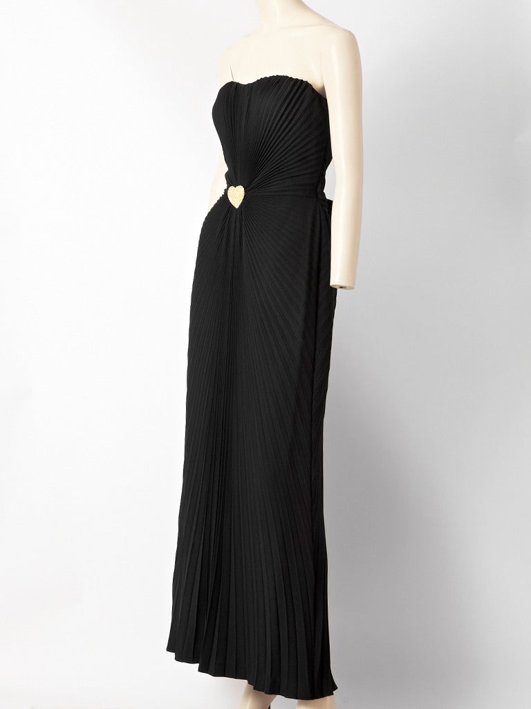 Azzaro, satin back, crepe, strapless,  bias cut , pleated gown with pleats coming from the center of the waist . Gold rhinestone heart at the center of the waist and a bow in the back. Built in corset.