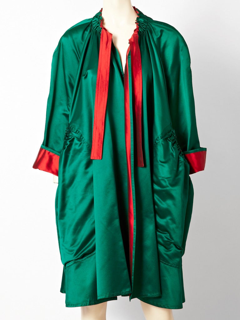 Bill Blass, satin, evening/opera coat. The outside of the coat is a deep
emerald green satin, with a ruched detail at the  collar and a tie at the neck. There are deep pockets that are also have  ruched detailing at the top. Interior of the coat is