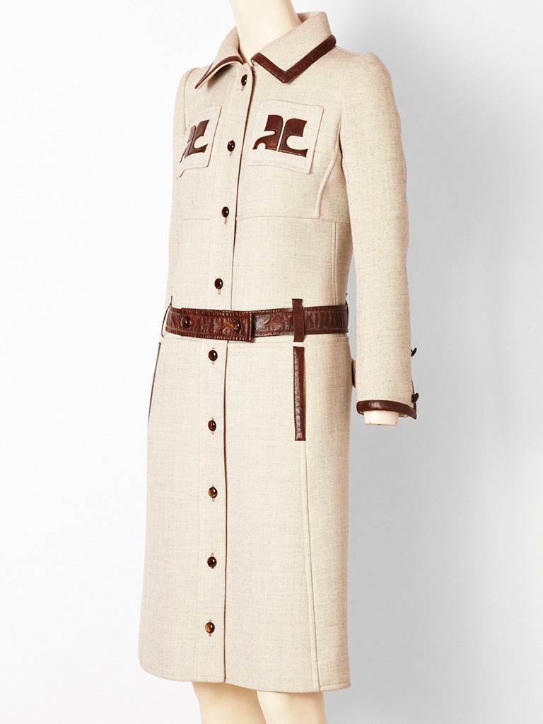 Courreges, beige, slim fitting coat in a heavy synthetic fabric that has a linen 
appearance. Coat buttons down the front, with leather trim at the collar, pockets and cuffs. Breast pockets have leather Courreges logo. Other detail is pockets on