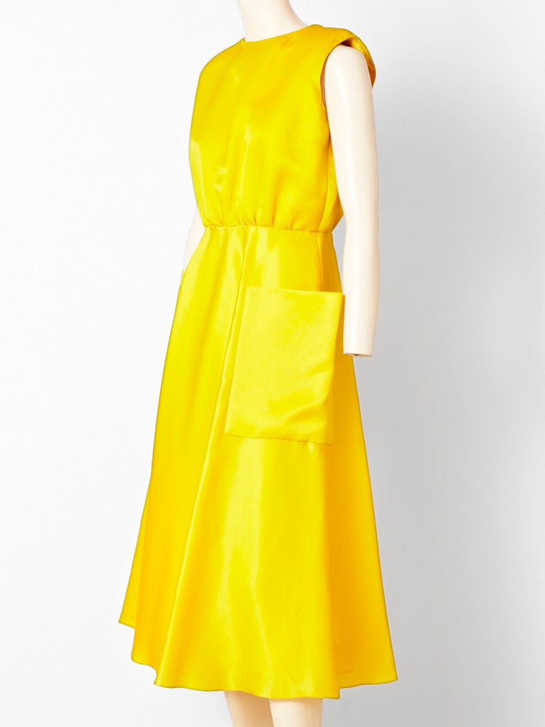 Chrome Yellow, organza , cocktail dress attributed to Bill Blass.
Simple sleevesss, jeweled neckline,  fitted, bodice and bias cut skirt with deep, large, patch pockets.