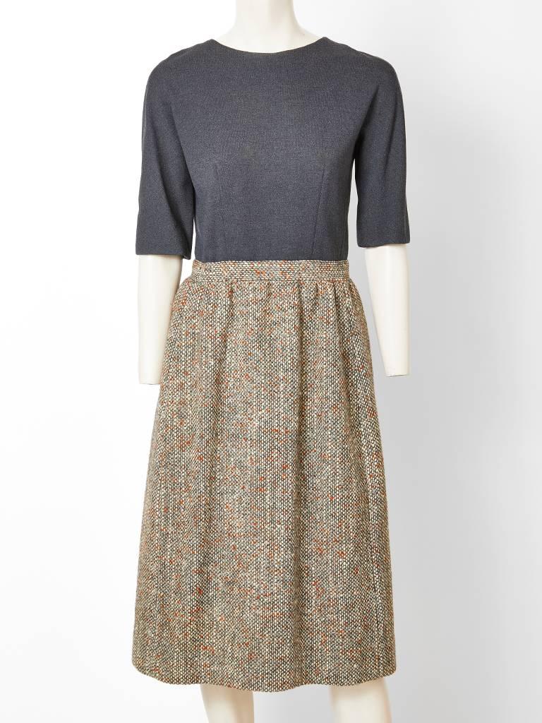 Norman Norell, wool tweed day dress with matching capelet. Ensemble is in an olive green tone wool tweed with specs of rust. Dress has elbow length sleeves with a round neckline. Bodice is in an olive tone wool jersey with a skirt in a wool tweed