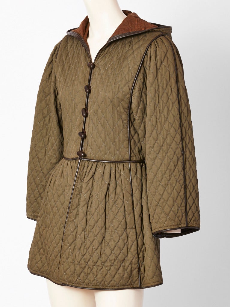 Yves Saint Laurent, iconic, olive green, quilted, jacket, having a fitted bodice,  then gathered at the waist ending at the thigh. Jacket has an attached hood and leather trim detail with toggle button closures.. C. late 70's.