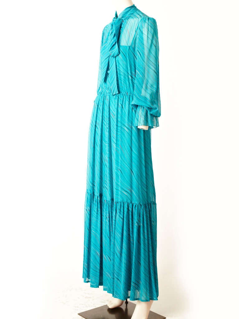 Guy Laroche, turquoise, printed chiffon 70's maxi dress. Long sleeves, with a tie at the neckline, gathered at the waist with a deep flounce near the hem.