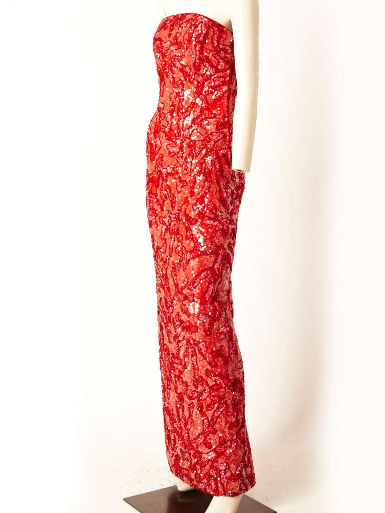 Halston, fitted strapless gown in a vermillion red color, encrusted in red and clear sequins. Red sequins form a coral branch pattern. Gown has a deep slit up the middle back for movement..C. 1980.