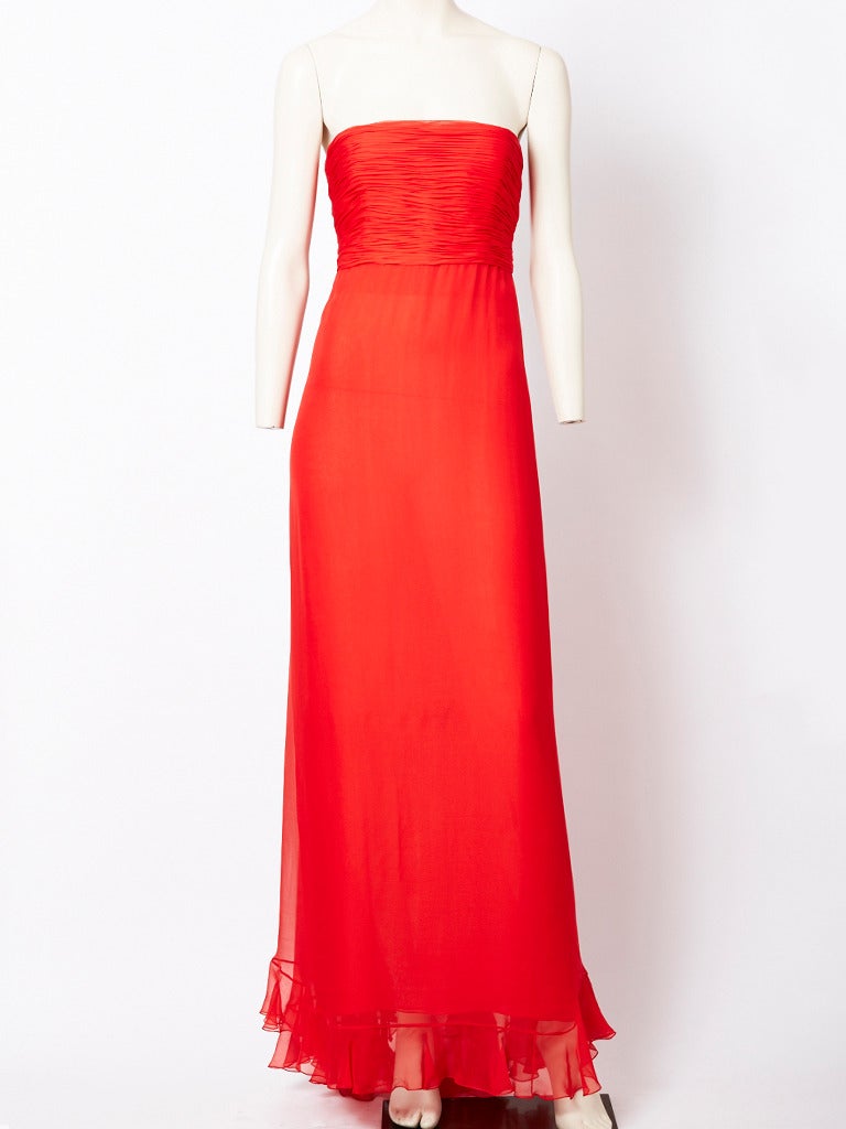 Oscar de la Renta, red, chiffon evening gown with matching ruffled shawl.
Gown is strapless having a ruched bodice and softly draped skirt with a ruffled hem. Back of dress has a draped ruffle going down the middle back to the hem.