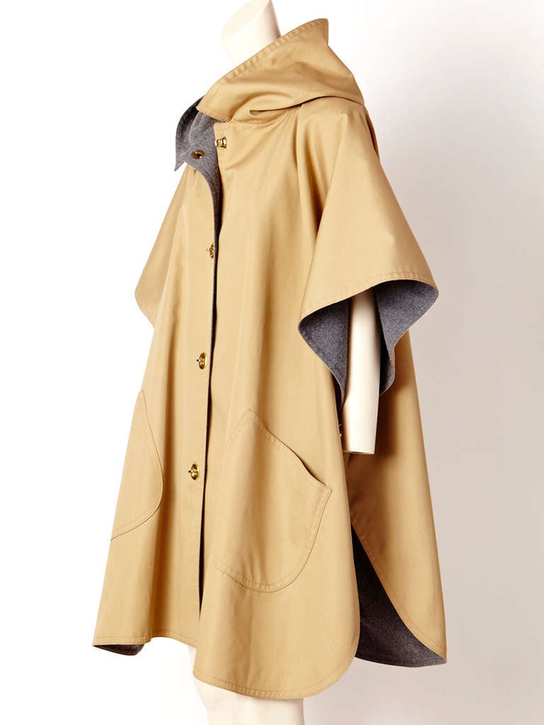 Bonnie Cashin,  hooded, raincoat/cape in khaki canvas with grey wool lining.
Signature brass toggle closures on the front and underarm creating a sleeve.
Deep side pockets.