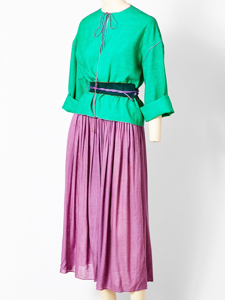 Geoffrey Beene, colorful raw silk ensemble, consisting of a jacket/top of 
a bright green that wraps at the waist with a belt and a tie at the neck. Gathered skirt is a dusty lavender with subtle hand smocking at the hips. Belt is suede with rope