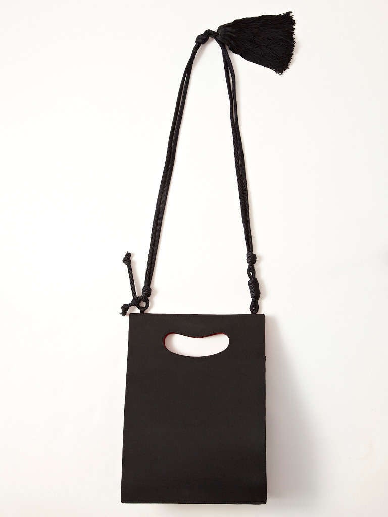 Yves Saint Laurent black, faille, shoulder bag with red faille interior. big black tassel detail on rope strap.