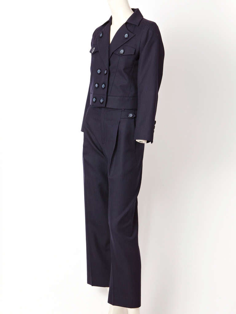 YSL, navy wool gaberdine, pant suit with a subtle chevron stripe.
Jacket is cropped, double breasted with button detail. Pant is straight legged.