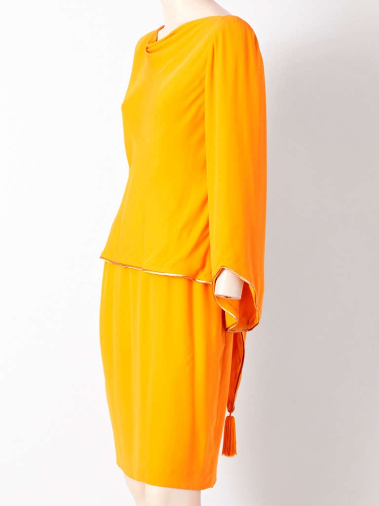 Pierre Balmain, marigold tone, heavy silk crepe 2 piece cocktail ensemble. Top is cut on the bias with a draped neckline and flared sleeve, Back forms a triangular point with a big tassel at the end. Skirt is straight. Sleeve and hem of the top is