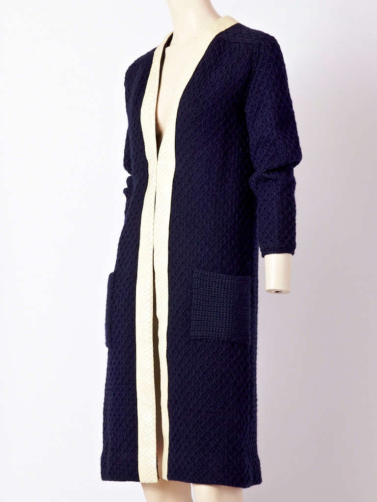 Bill Blass, navy, diamond pattern,  wool knit, long cardigan with ivory python trim around the neck and down the front. Side pockets are crocheted. C. 1970's.