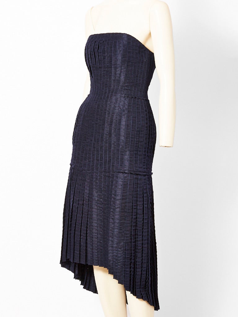 Isabel Toledo, navy, strapless, taffeta pleated cocktail dress with asymmetric hem. Dress is made of vertical, textured, ribbon like strips. The body is entirely
pleated. Bodice pleats are stitched down. The balance of the dress has small