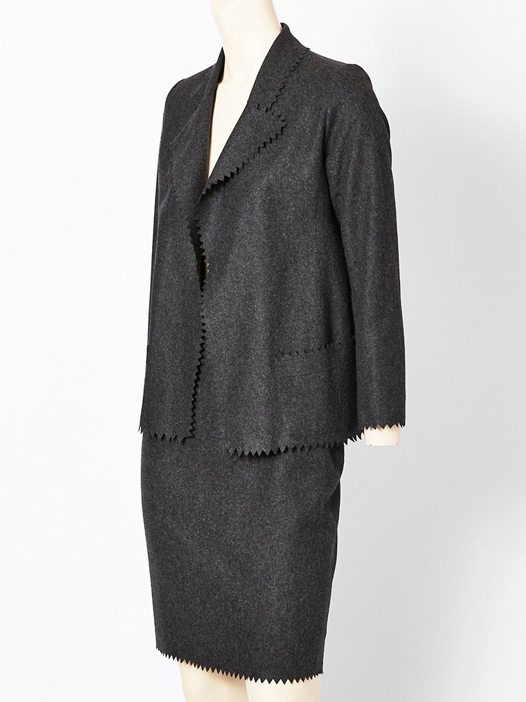 Valentino, grey, wool flannel skirt suit with a Blazer style jacket with hip pockets and a straight pencil skirt. Jacket edge, pockets and skirt hem have hand pinked detail. There are no closures on the jacket.