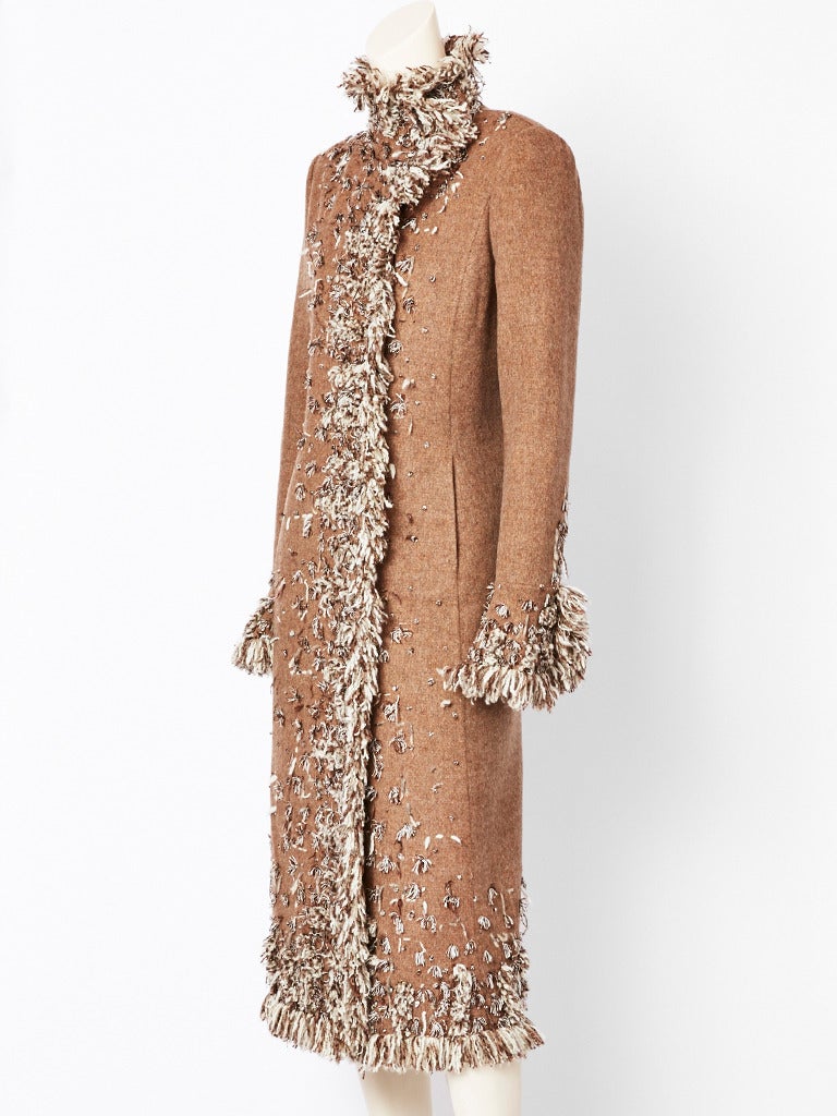 Oscar de la Renta, bohemian inspired, taupe, double face, cashmere coat having an embroidered fringe, in ivory, taupe and brown. Slightly fitted silhouette with a high neckline. Hidden covered snap closures inside of the coat.