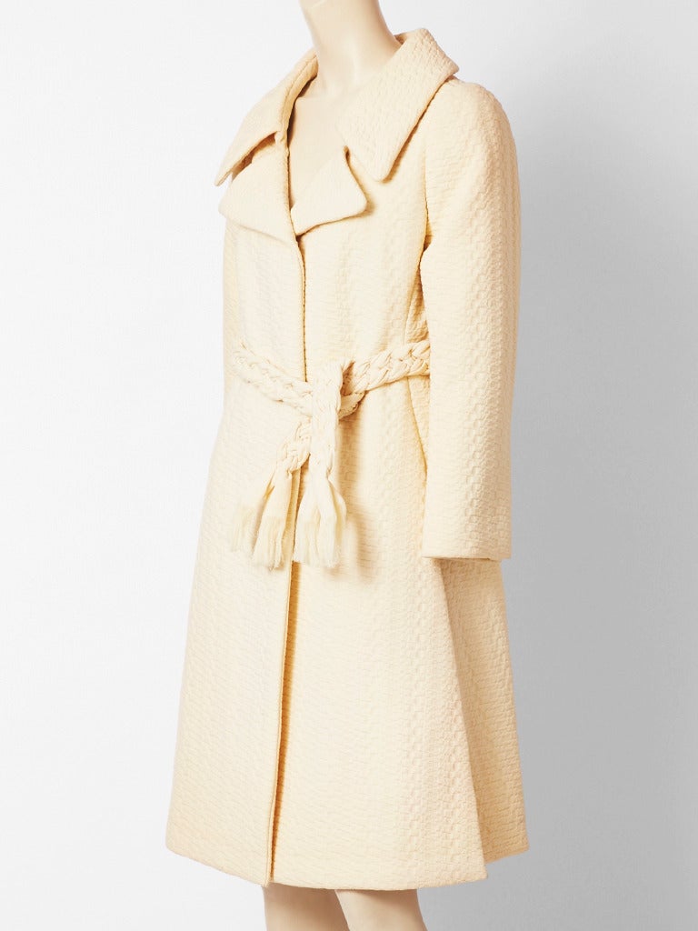 Galanos, ivory, textured, wool coat with a fitted bodice and flared body.
Wide lapels, having a braided belt detail. C.1970's