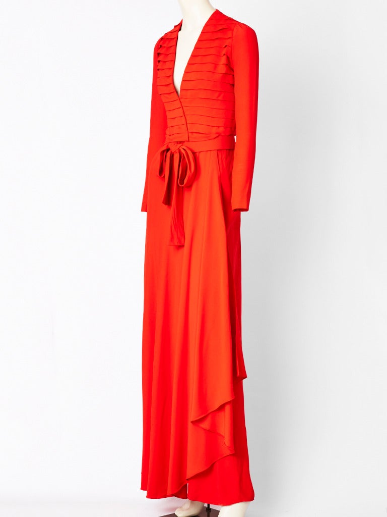 Heinz Riva of Roma, red crepe, gown having a bodice that crosses over with a v neck, and horizontal pleating detail. Long narrow sleeves. Skirt is bias cut with an asymmetric slit. There is a generous, red self belt that ties at the waist.
Late