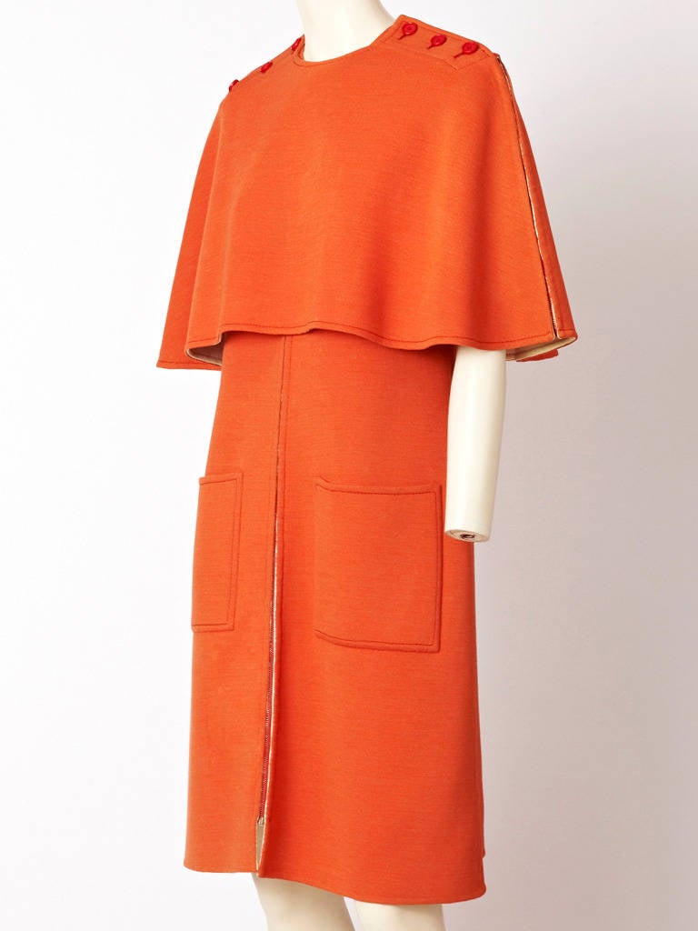 Dior, persimmon tone, double face wool knit Haute Couture day dress with matching caplet. Dress has short sleeves front pockets and zips up the front.
Cape has rounded neckline and buttons at the shoulder with zippers down from
the shoulder to the