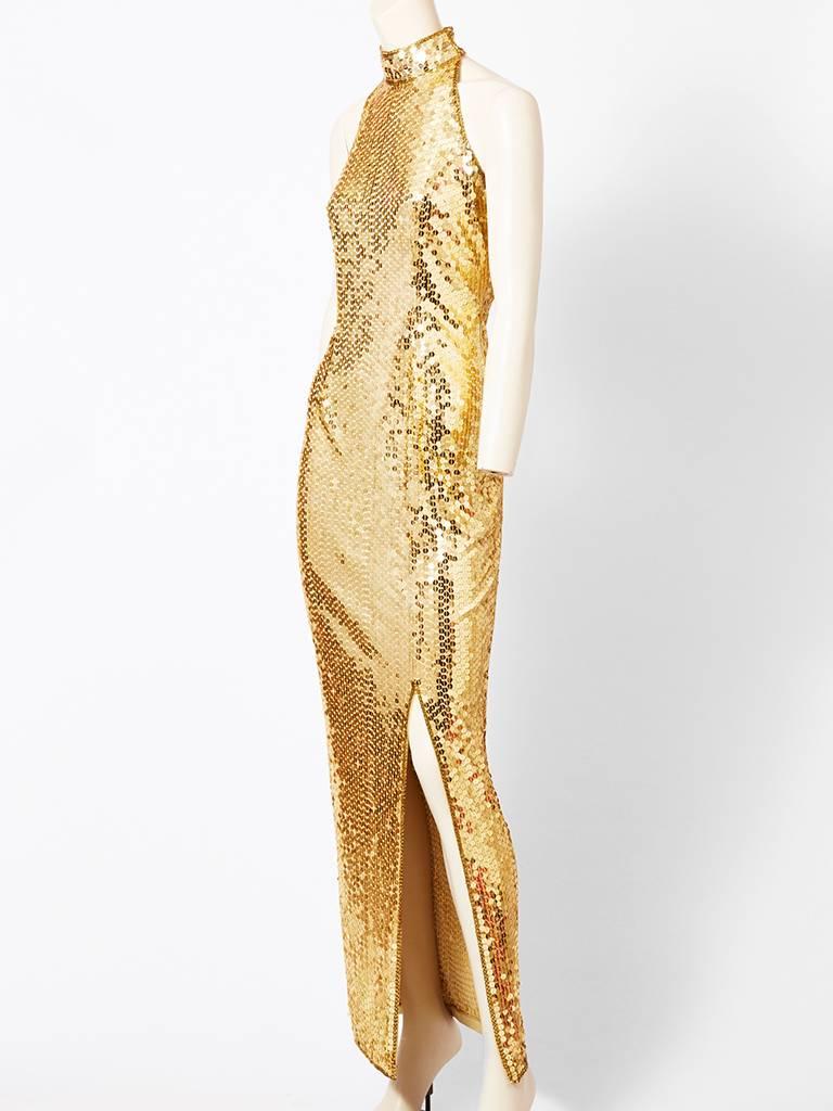 Ted Lapidus, fitted, halter nect, cut, fitted gown encrusted with large gold paiettes. Dress has slit at the side exposing the thigh.