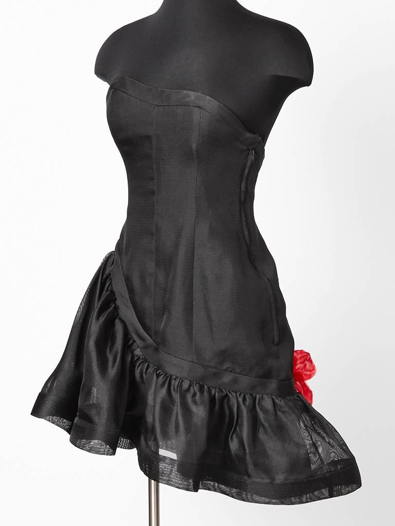 Yves Saint Laurent, black gazar, strapless, cocktail dress having a fitted bodice
and an asymmetric flounced hem with silk, appliqued, red, poppy, flowers on the lower back.  