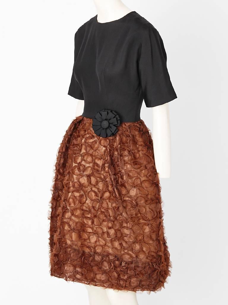 John Moore black and brown cocktail dress form the early 60's. Having a black 
Crepe, jeweled necklines fitted bodice with sleeves up to the elbows and a brown skirt with appliquéd raised flowers in a sculpted shape.