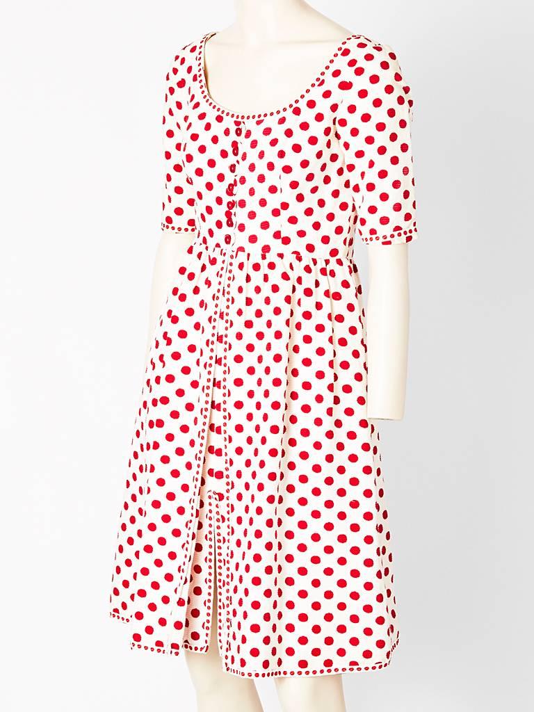 Oscar de la Renta, cotton Ottoman, red and ivory polka dot, empire waistline
day dress having an inverted pleat below the waist going down to the hem.
The cotton ottoman fabric gives the dress body . Small polka dot piping, edging, detail along