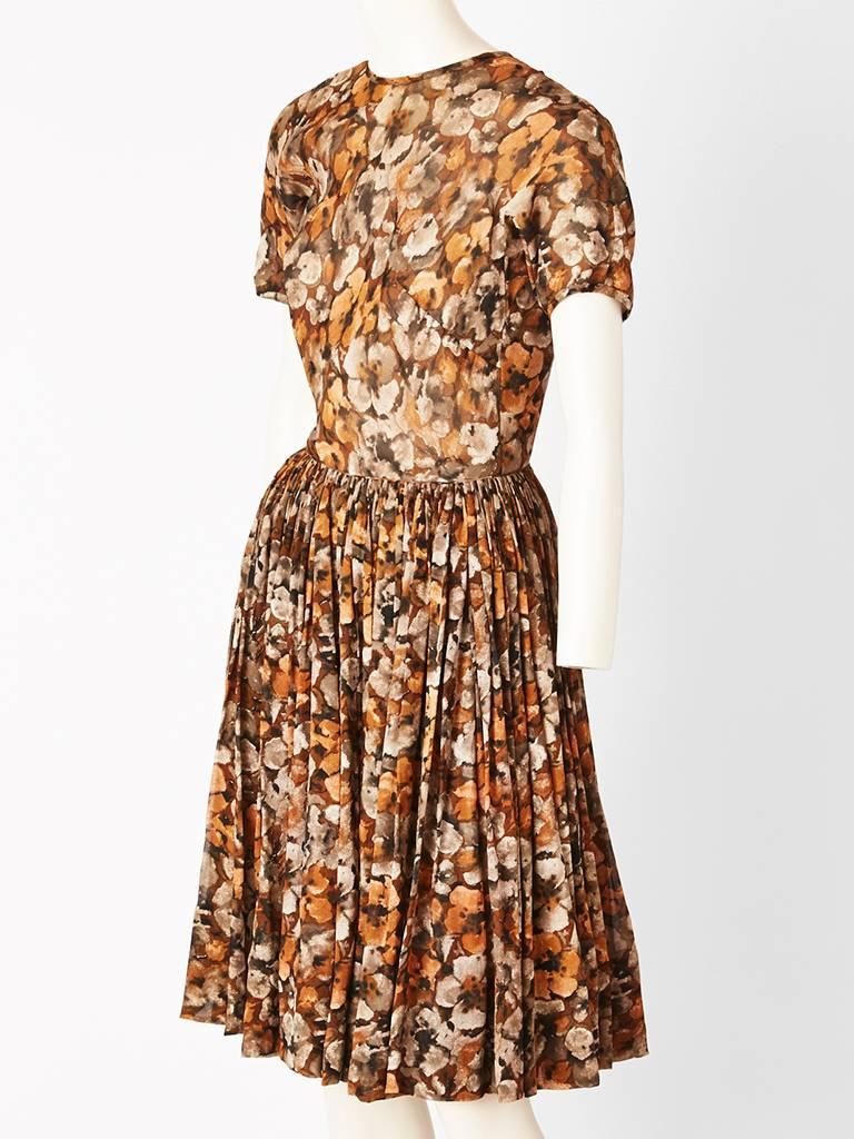 James Galanos, floral print, chiffon day dress, having a jewel neck line, short sleeves, fitted bodice, and a full gathered skirt , Soft shades of browns and greys. Back has an off center closure detail with buttons going all the way down the back.