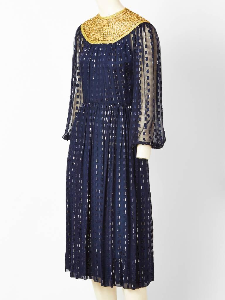 Navy blue, silk chiffon, with gold lurex, long sheer sleeved, dress with a slightly gathered skirt. Dress is embellished with vertically placed bugle beads and a gold beaded, 
